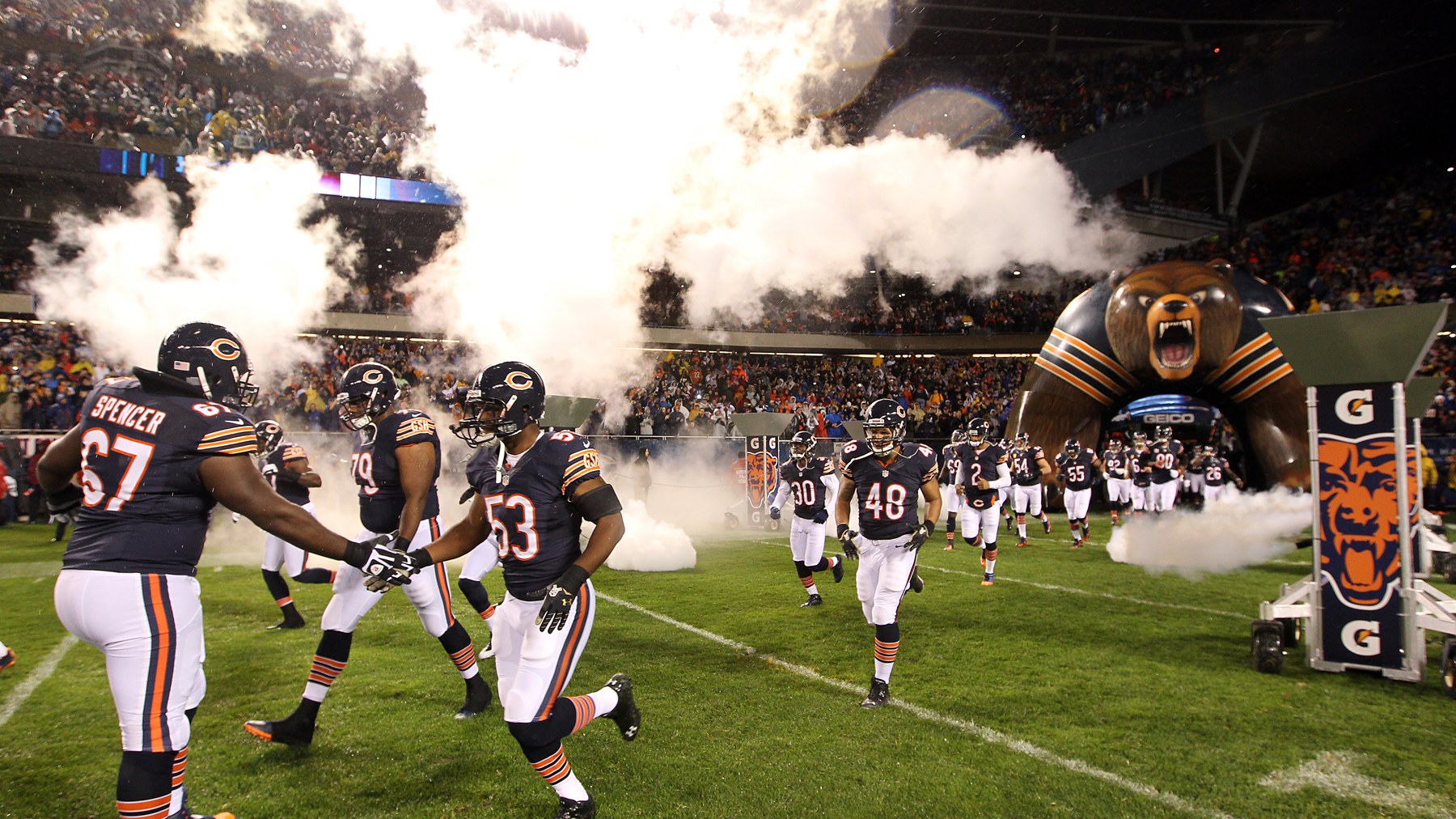 Chicago Bears players running onto the field at Soldier Field through smoke