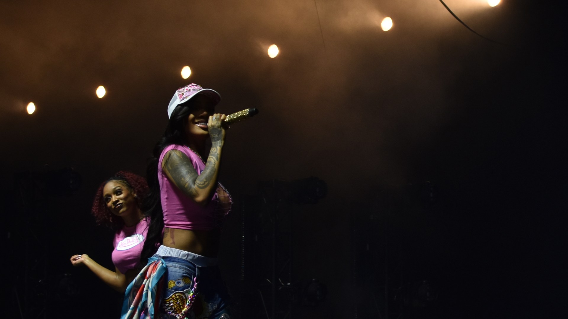 GloRilla performs on stage in a pink top holding a microphone