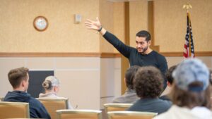 Abdul El Sayed speaking to voters at a campaign meeting with his hand raised