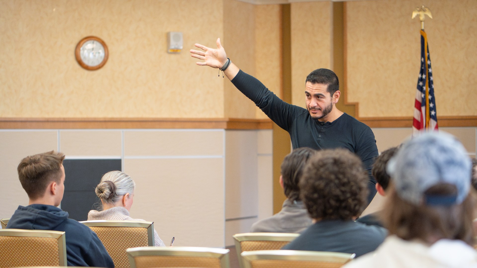 Abdul El Sayed speaking to voters at a campaign meeting with his hand raised