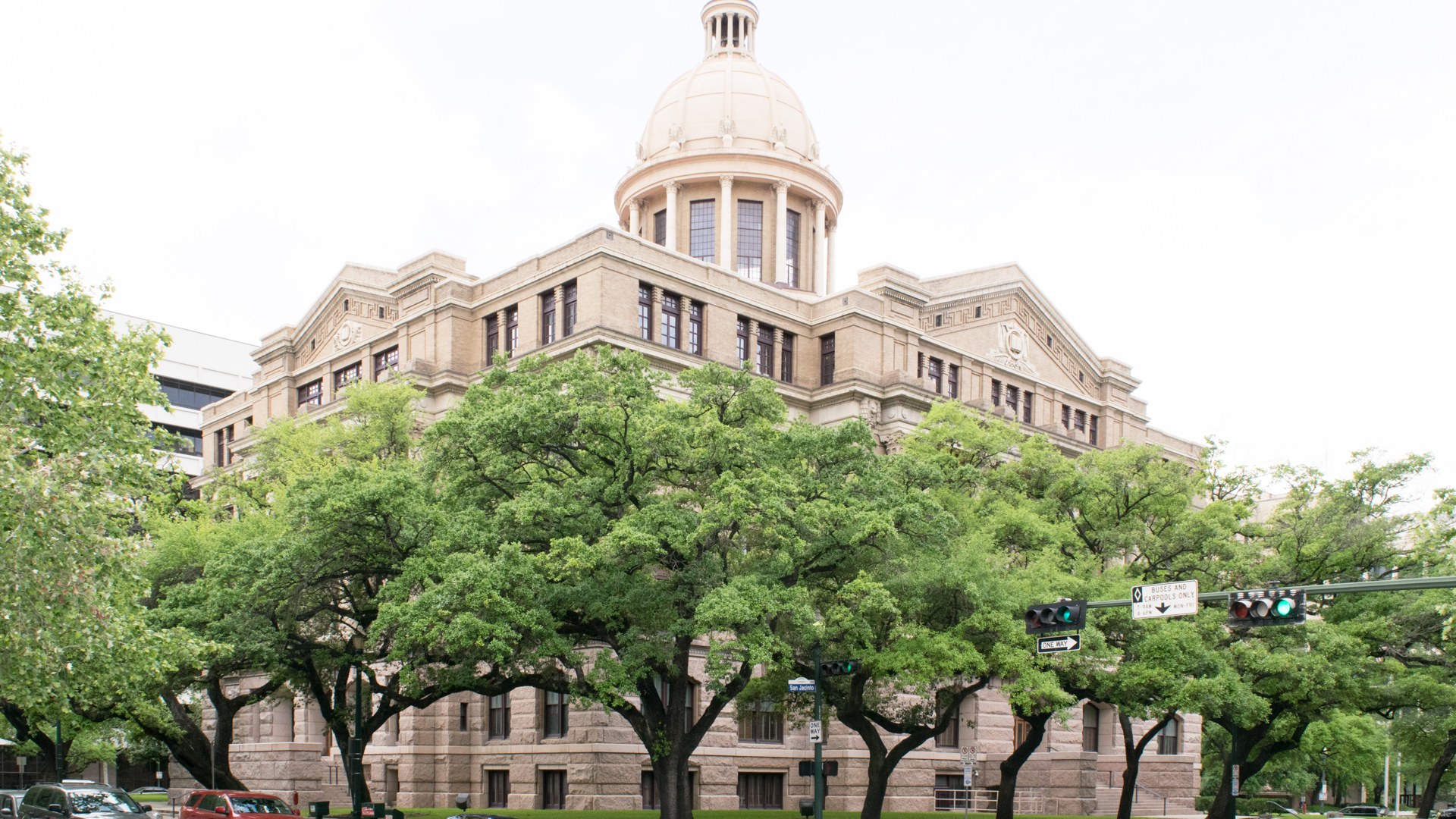 The 1910 Harris County Courthouse in Houston under a blue sky with palm trees in front