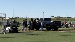 The black pickup truck sits on the turf at Stryker Sports Complex in Wichita as families gather nearby
