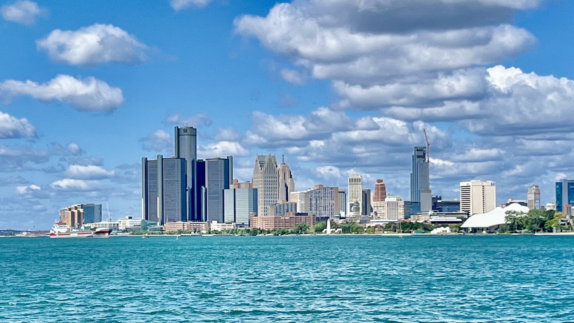 Detroit skyline across the river under a bright sky with clouds