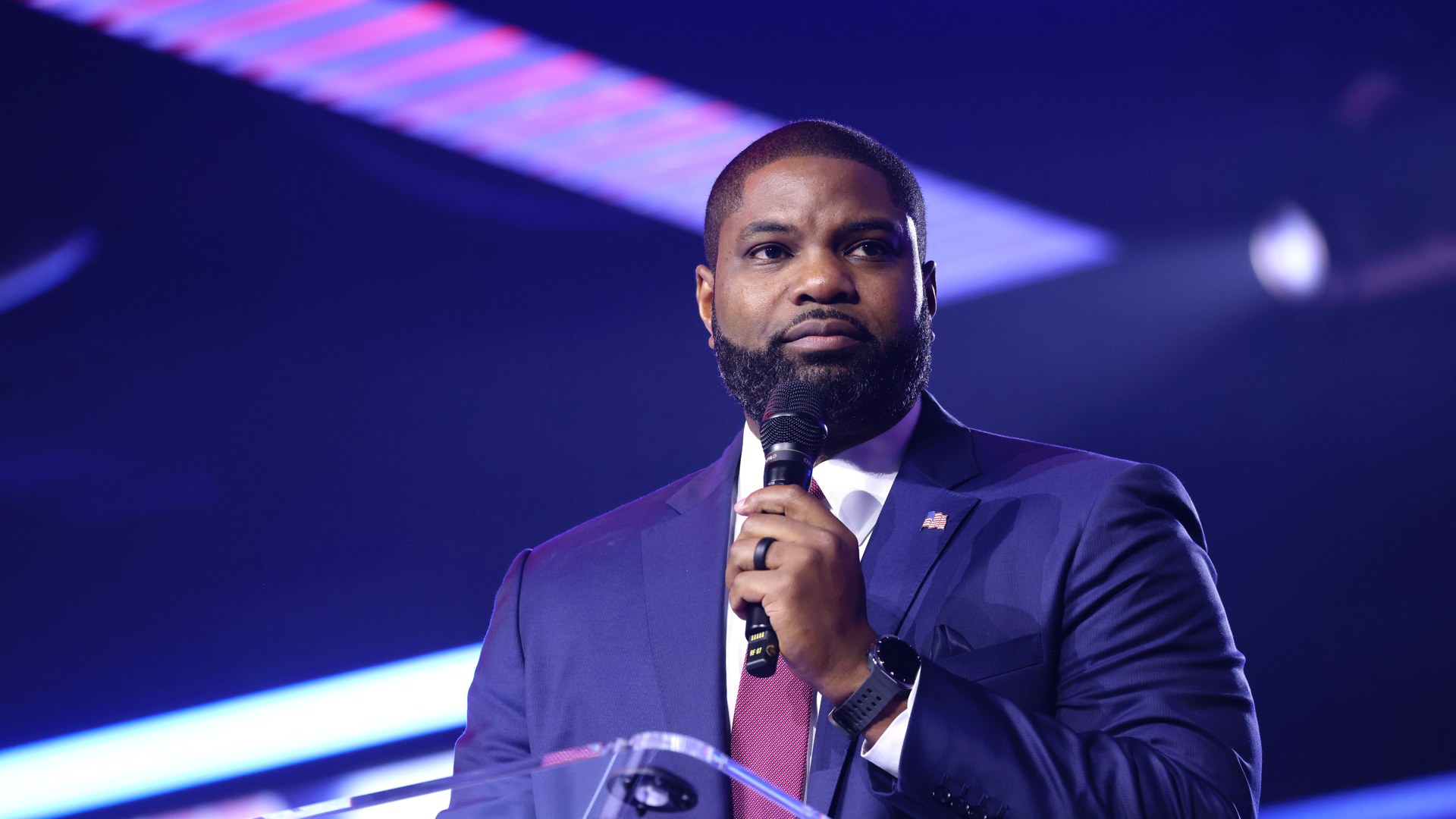 Byron Donalds speaks into a microphone at a podium on stage