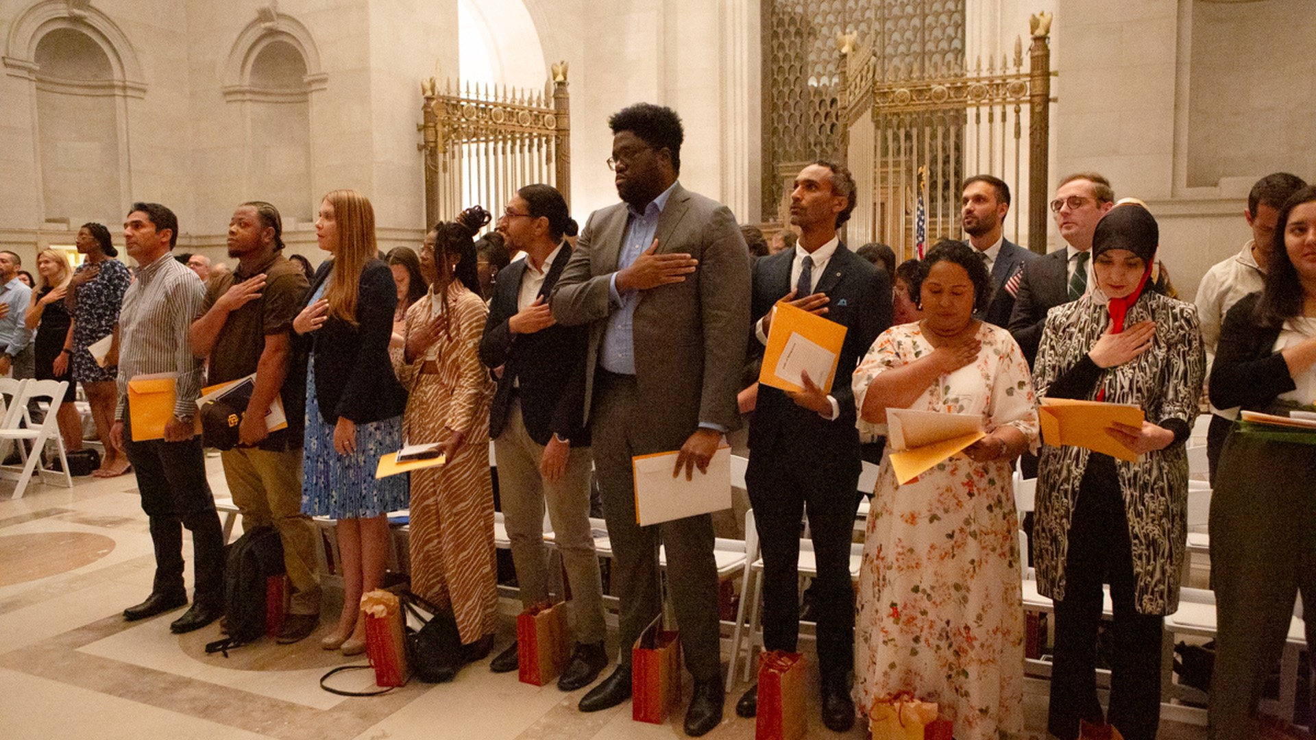 New citizens stand with hands over their hearts during a naturalization ceremony in Washington