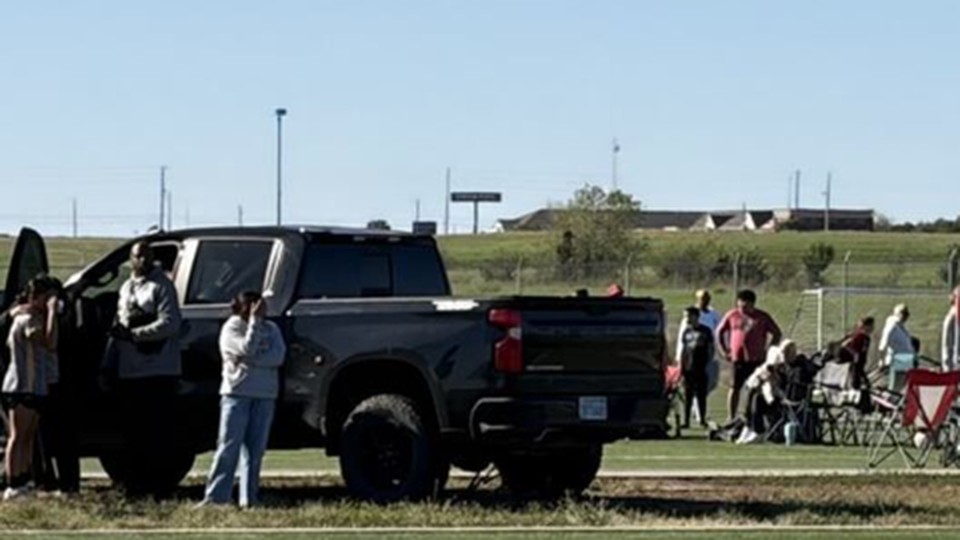 A closer view of the pickup truck stopped on the soccer field with its driver side door open