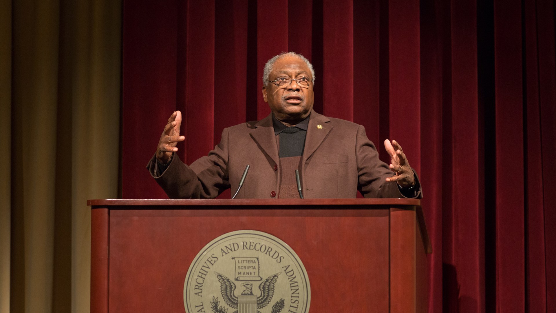 Representative Jim Clyburn speaking at a podium with both hands raised