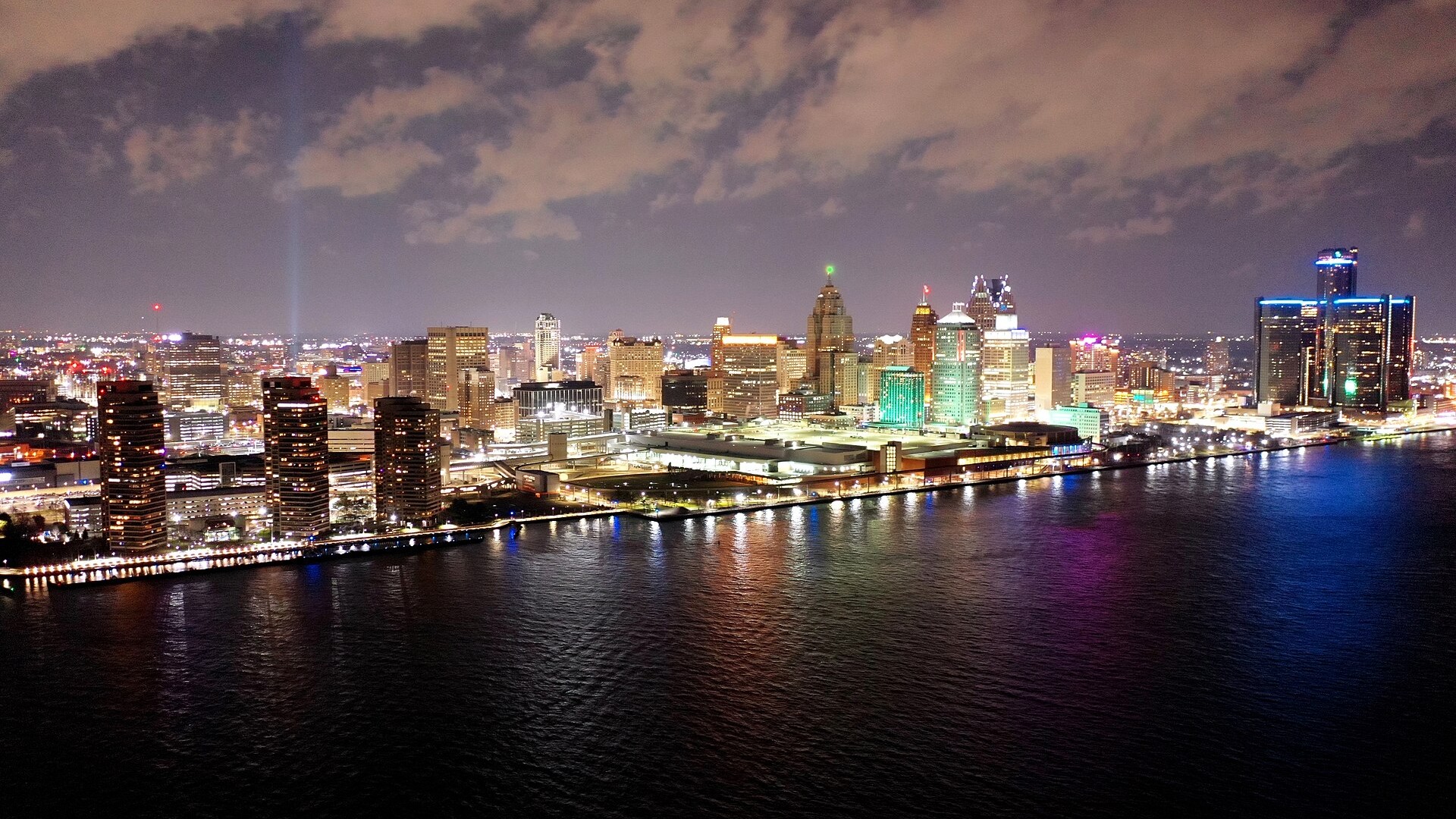 The Detroit skyline at night seen across the river with lights reflected on the water