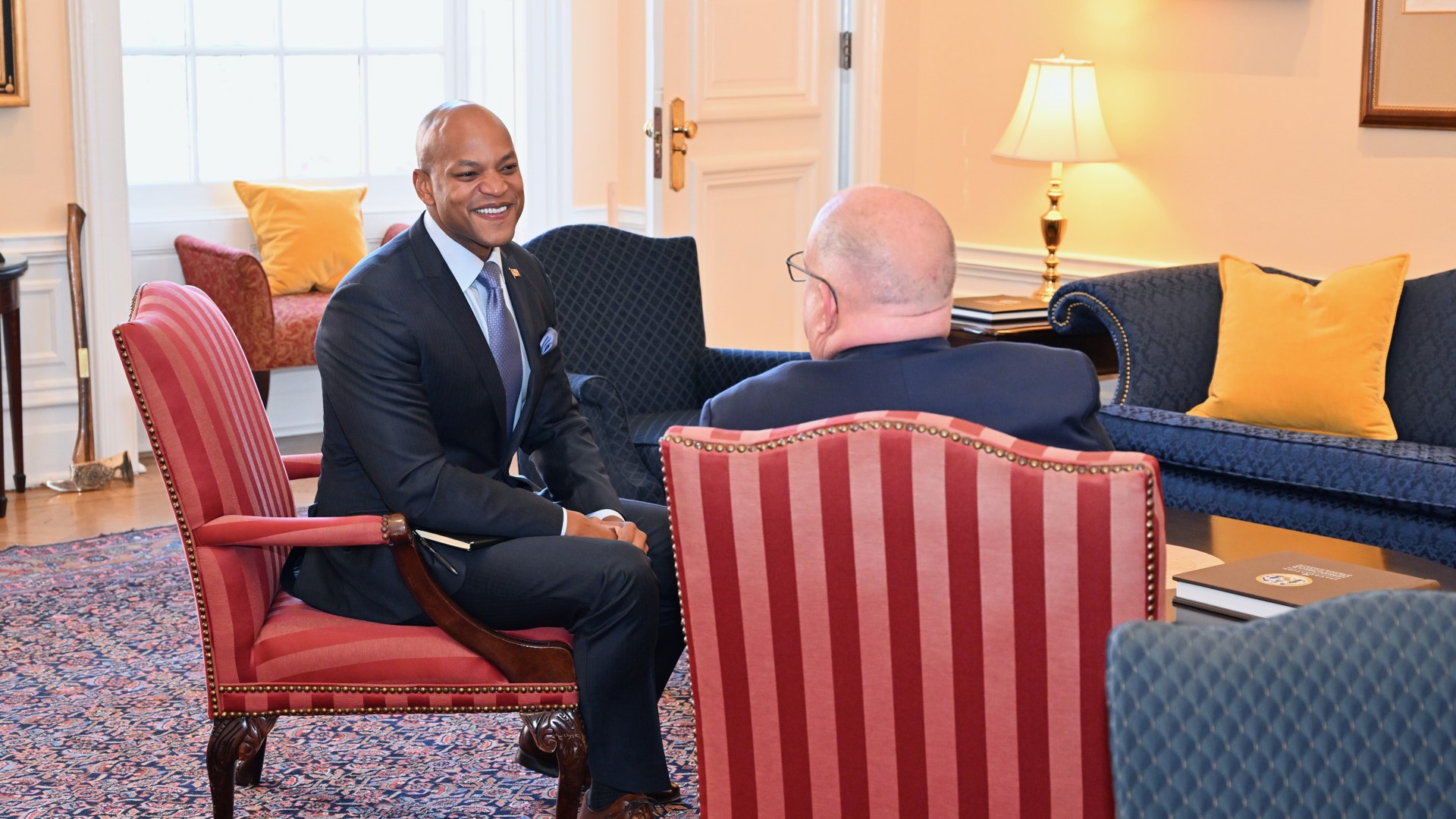 Wes Moore smiles while seated in a meeting inside a Maryland office