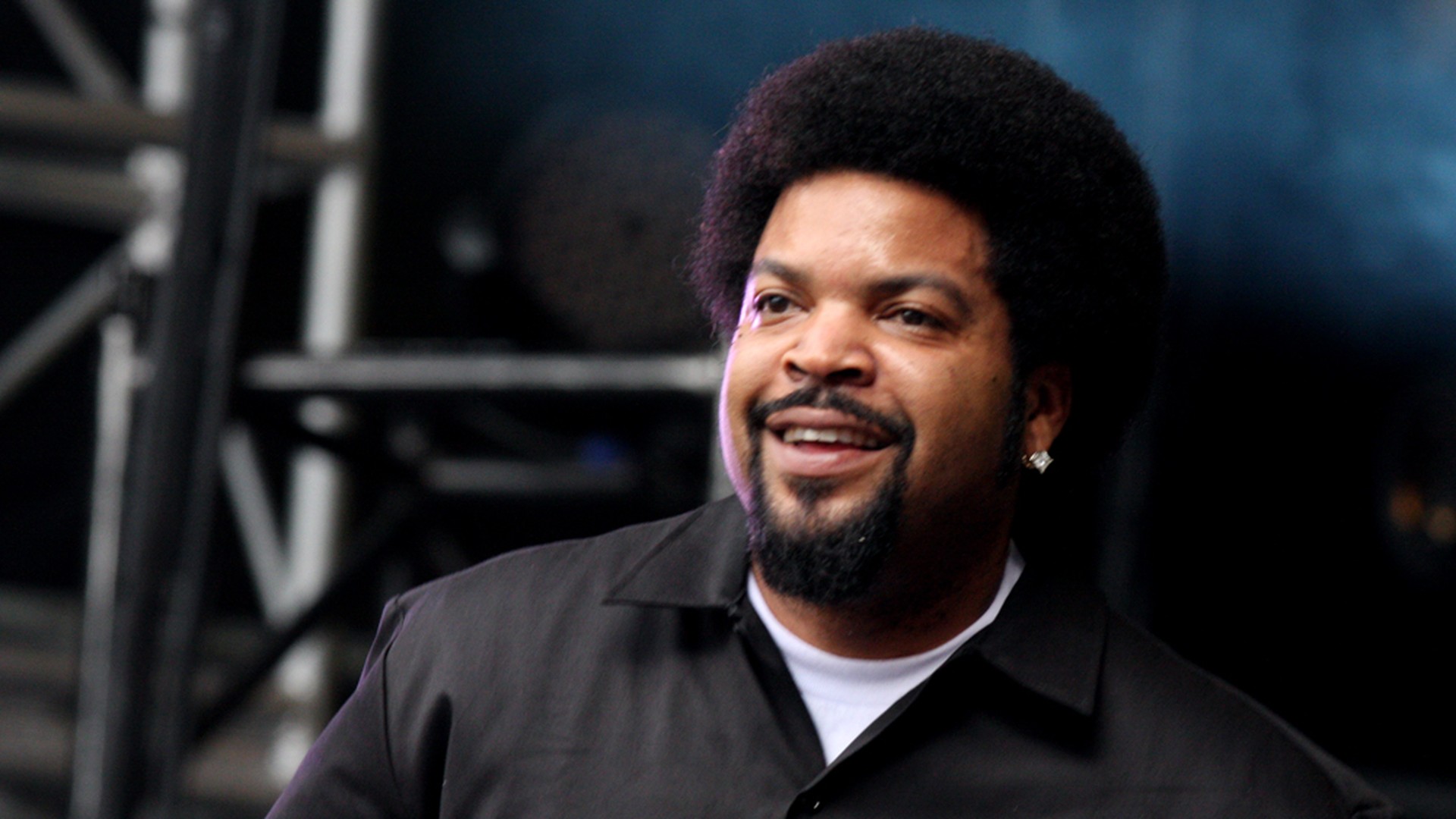 Ice Cube smiles on stage in a black shirt