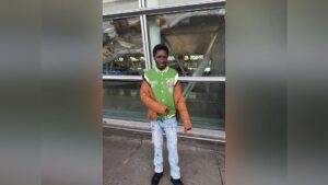 Javits Frimpong standing outside in a green varsity jacket and jeans