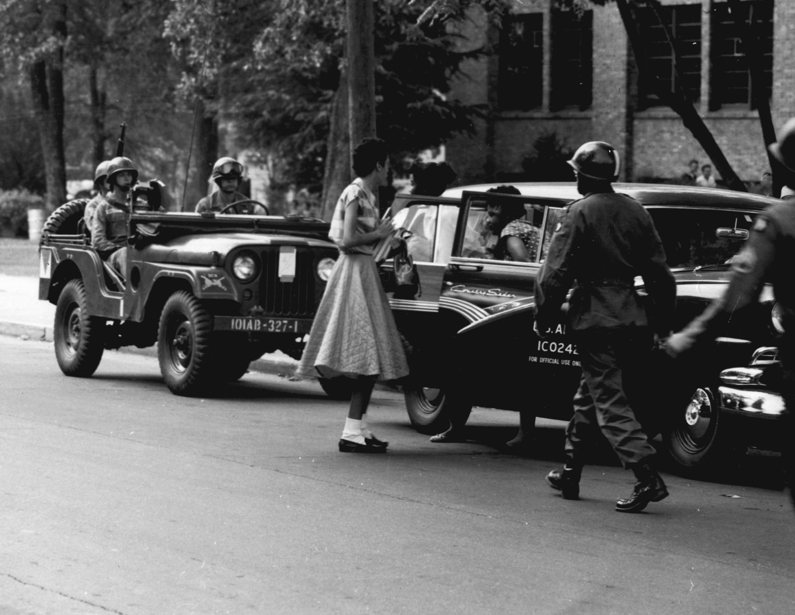 A soldier of the 101st Airborne Division holds the door of an Army staff car as a Black student arrives at Central High School in Little Rock in September 1957