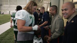 Nick Mangold in his New York Jets number 74 jersey signing a football for service members