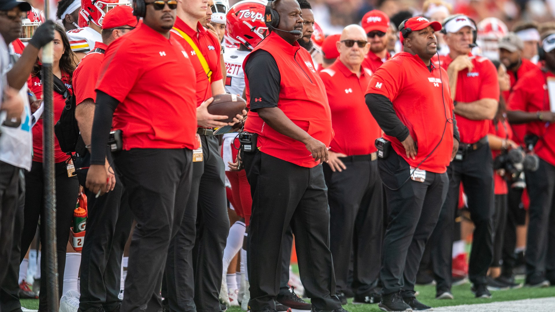 Mike Locksley stands with members of his coaching staff on the Maryland sideline