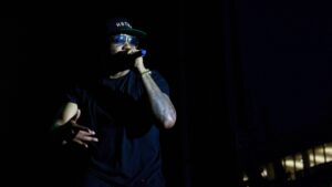 Nas performing live on stage holding a microphone