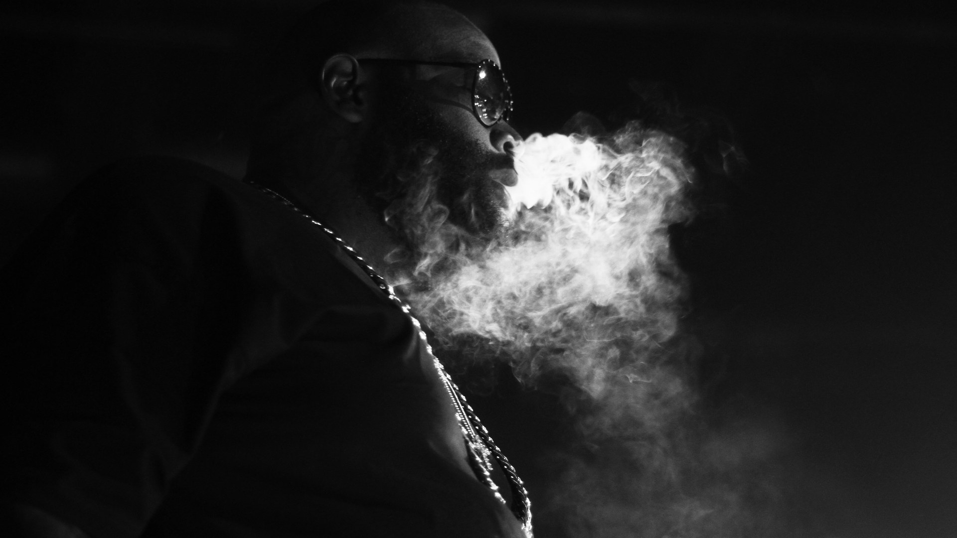 Rick Ross performing on stage in black and white during the Mastermind Tour