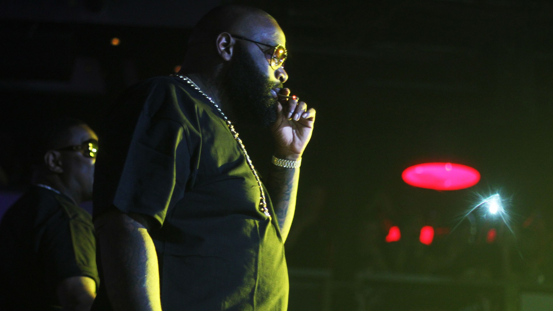 Rick Ross on stage in profile wearing dark glasses and a heavy chain
