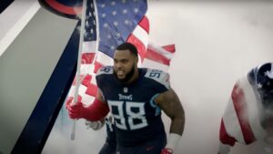 Jeffery Simmons in a Tennessee Titans uniform carrying an American flag onto the field