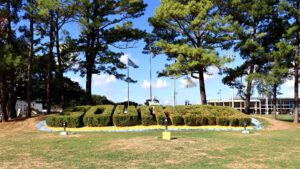 The word Southern spelled out in trimmed hedges on a grassy hill on the Southern University campus in Baton Rouge, with pine trees, flags and the stadium behind it