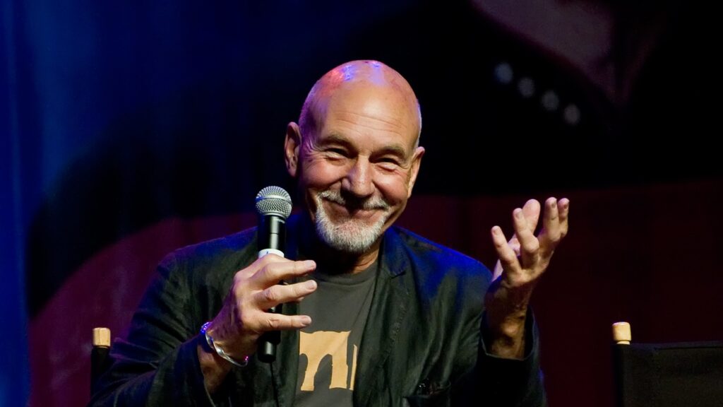Patrick Stewart smiling while speaking into a microphone at a Star Trek convention in 2011