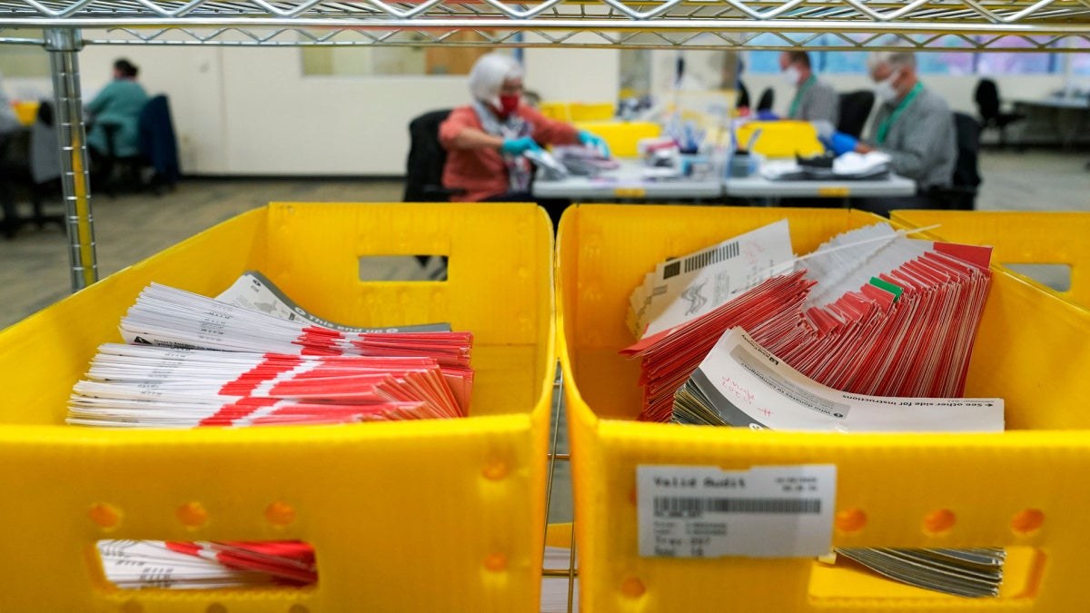 Mail ballot envelopes sorted in yellow trays at a Washington ballot processing center